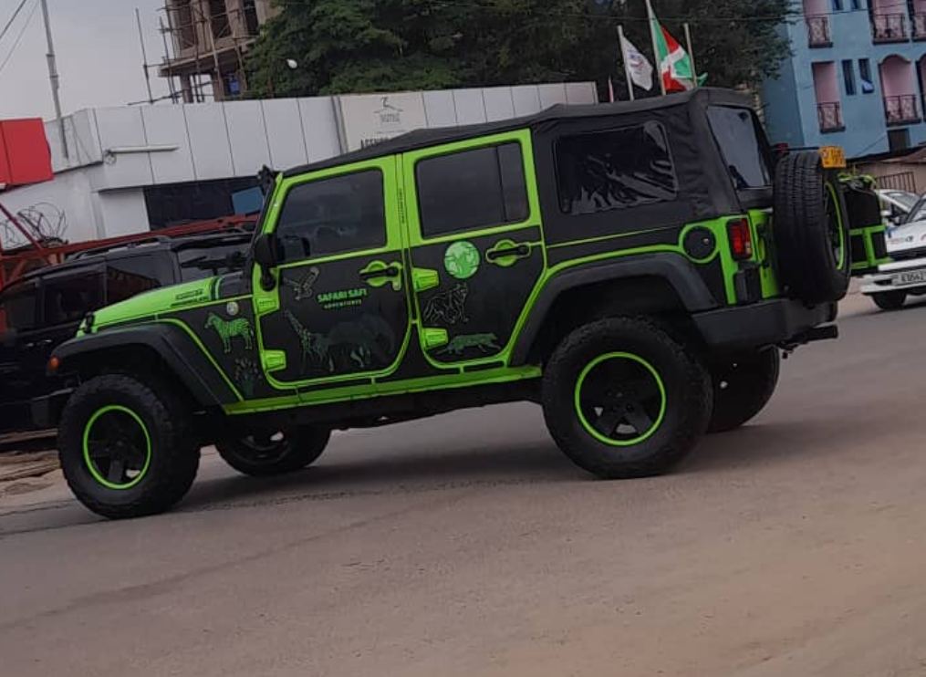 Side profile of the Safari Safi Jeep Wrangler with animal decals, driving through Bujumbura